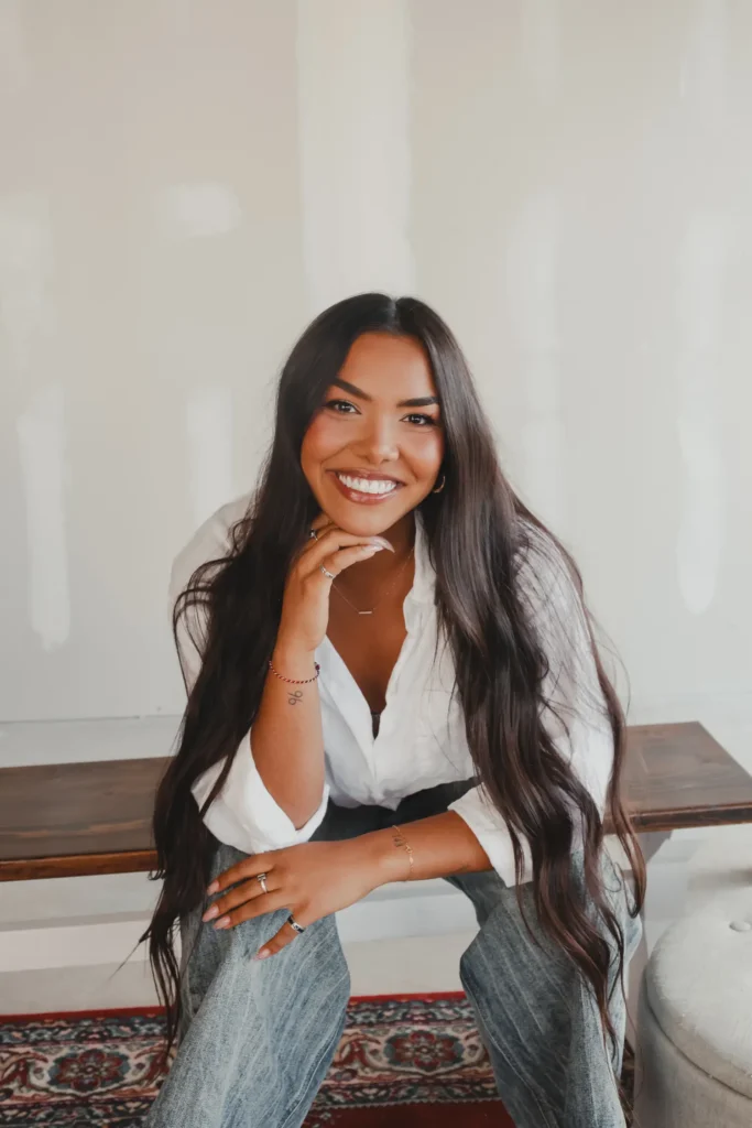 Smiling woman in a white shirt resting her chin on her hand