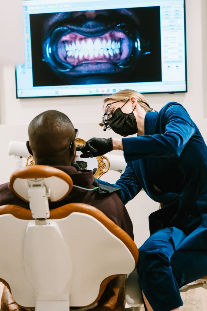 Dentist examining a patient at Vigée Dental, with a scan of his teeth on the screen above