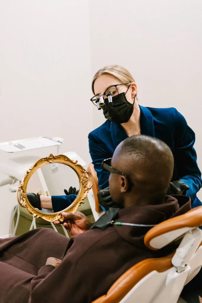 Dentist showing a patient his smile in an ornate gold hand mirror at Vigée Dental