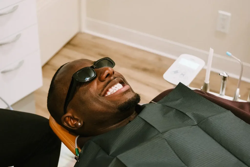 Smiling patient in sunglasses reclining in a dental chair