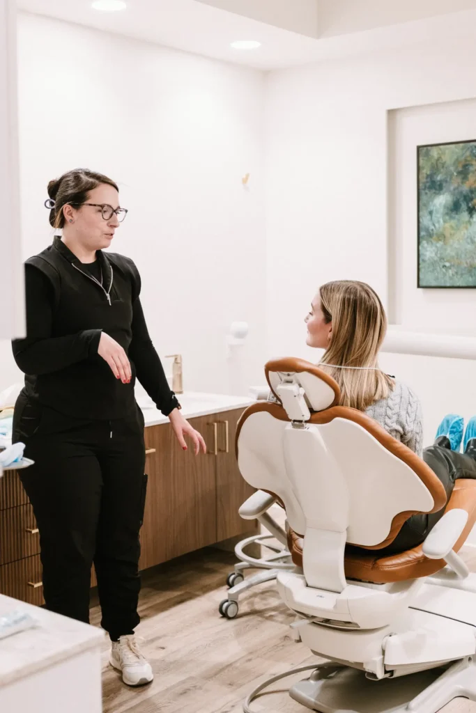 Dental team member in black scrubs talking with a patient in a treatment chair
